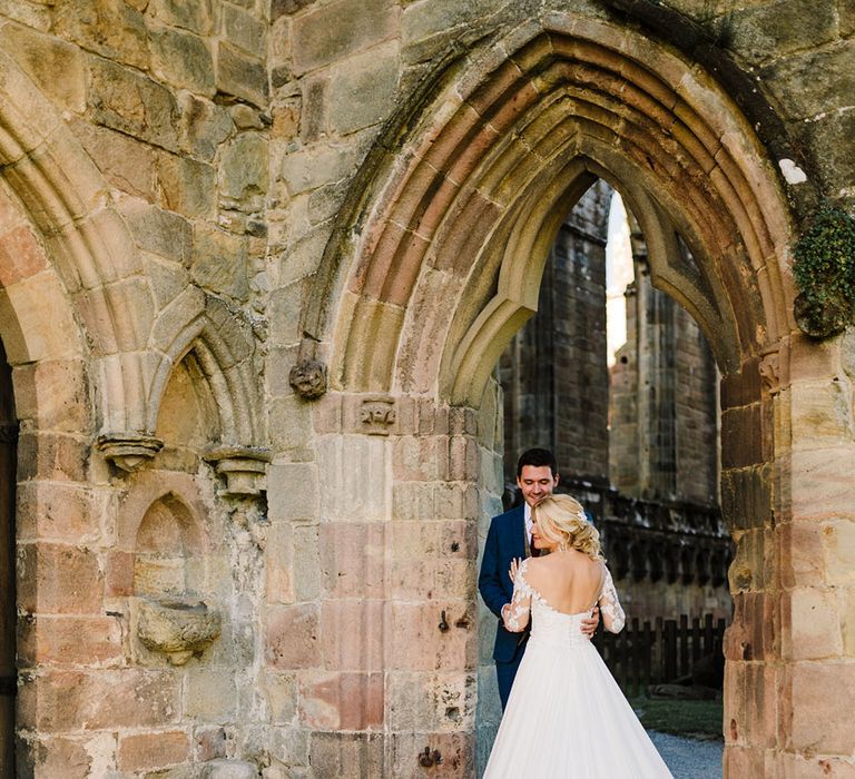 Bride wears low back Pronovias lace wedding dress with exposed buttons to the back