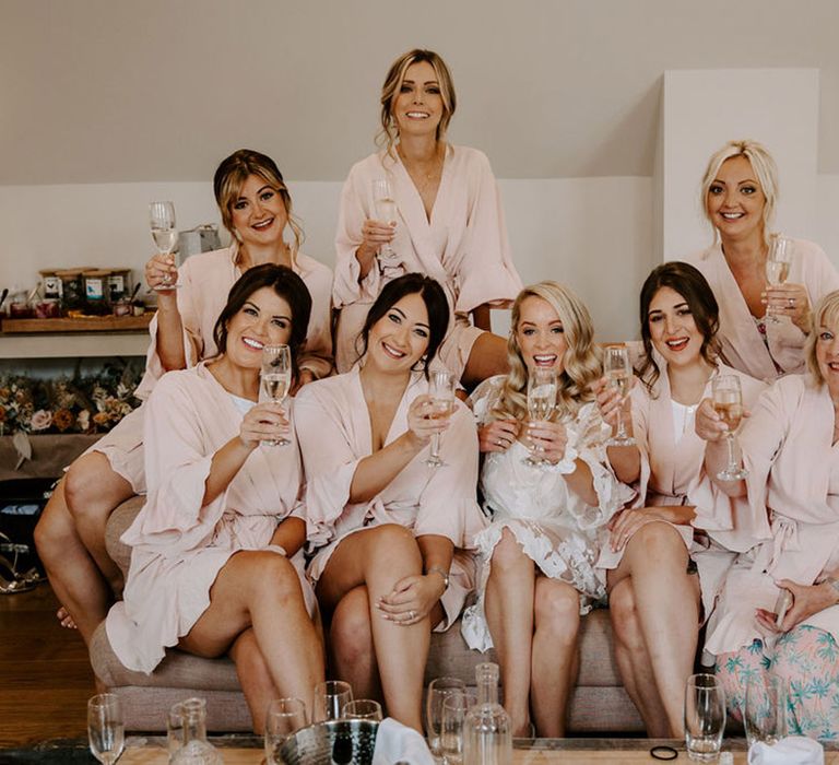 Bridesmaids in matching pale pink robes and mother of the bride with the bride in a white lace robe