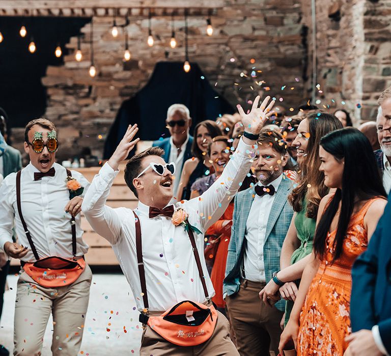 Flower dudes throw confetti down the aisle ready for the bride in cool retro sunglasses