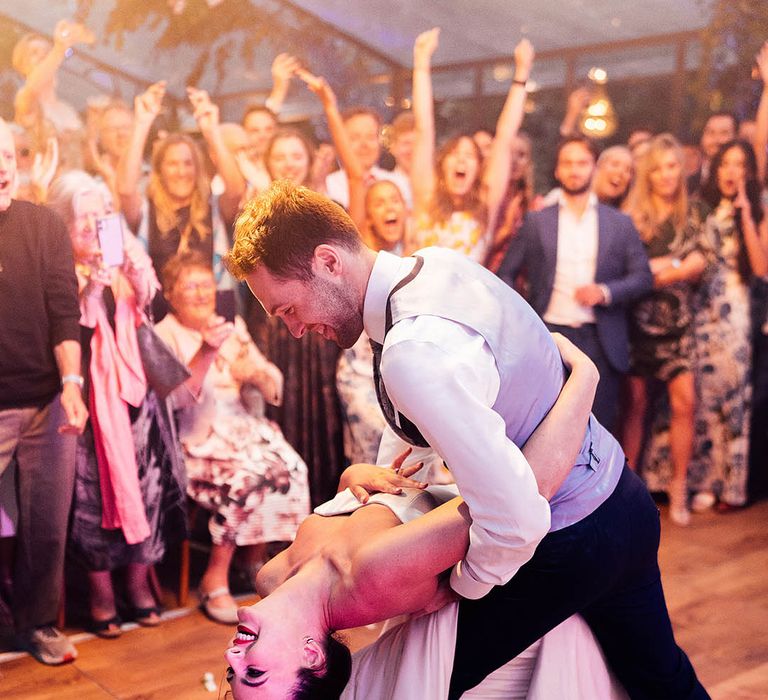 Groom dips the bride low for their first dance after having dance lessons 