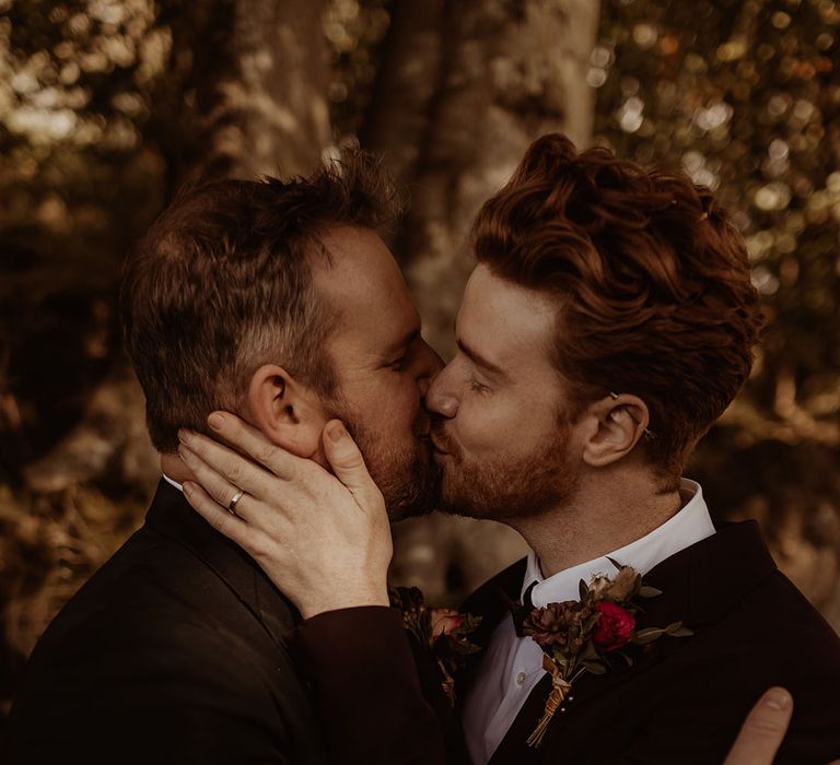 Grooms embrace and share a kiss for their black tie autumnal wedding captured by an LGBTQ photographer 