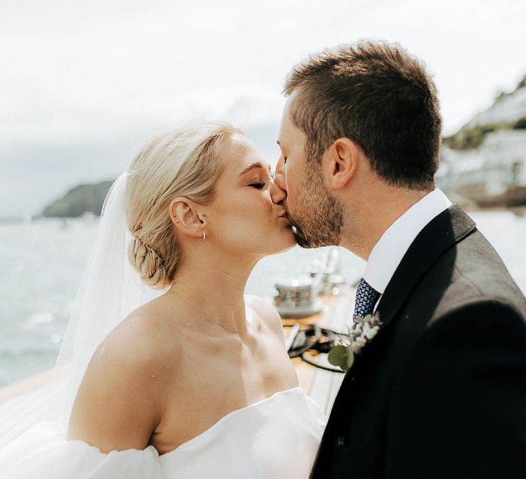 Bride with blonde hair and wearing Jesus Peiro wedding dress kisses her groom outdoors 