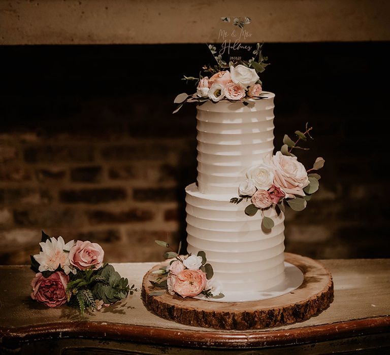 Two tier wedding cake complete with white frosting and pale pink floral decor 