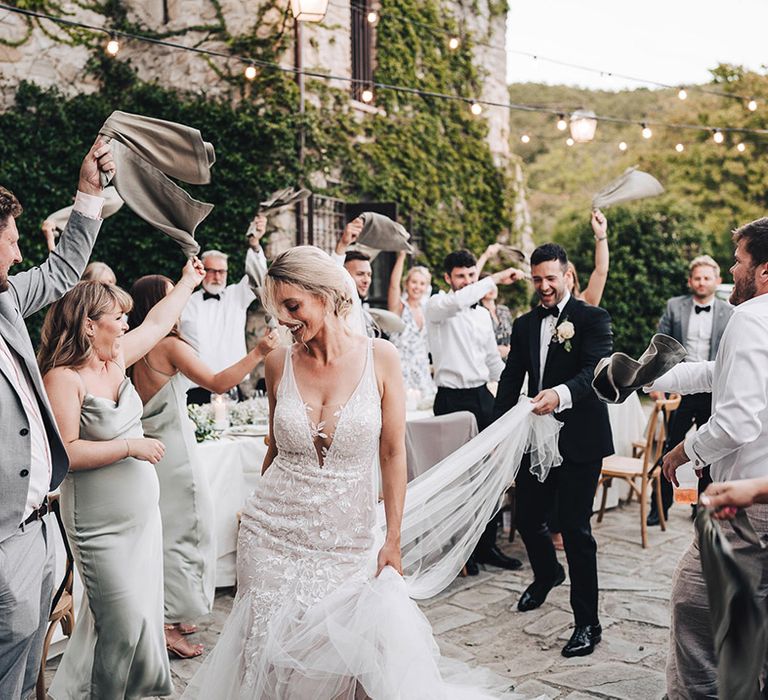 Wedding guests spin napkins in the air during outdoor Italian wedding reception