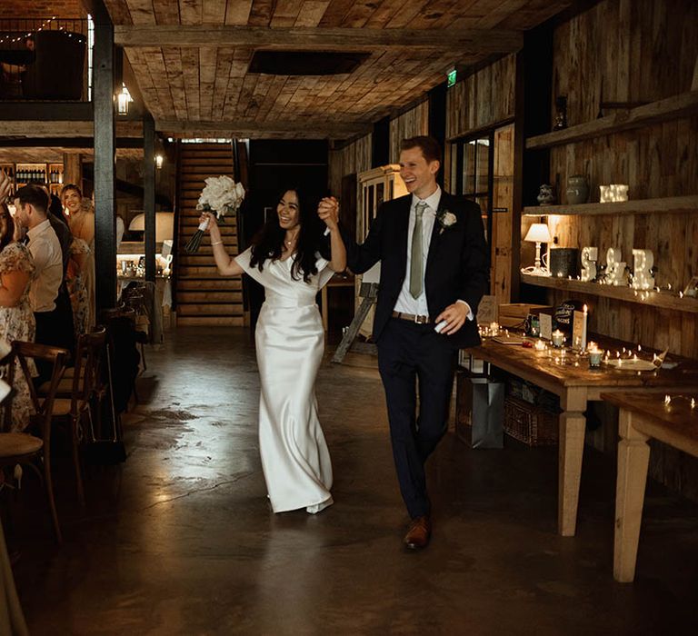 The bride and groom celebrate as they enter their wedding reception together 