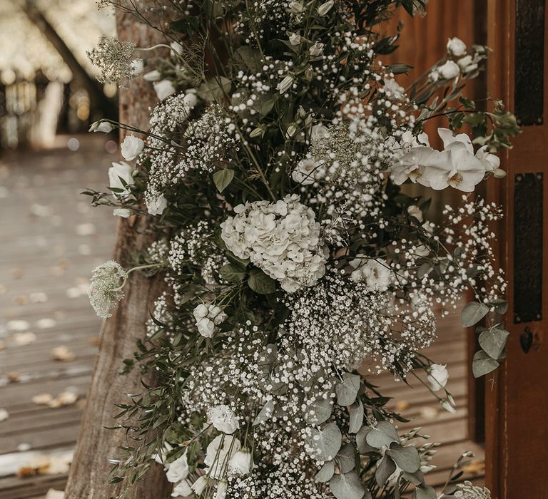 Roses, orchids, hydrangea, and orchids in white make up a wedding flower column arrangement 