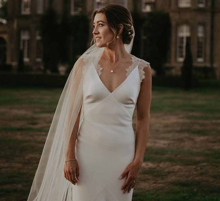 Bride wears fitted Savannah Miller wedding dress with scallop lace edge detailing