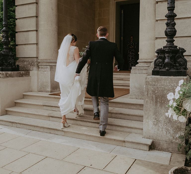 Bride in Savannah Miller wedding dress walks alongside her groom to Hedsor House 