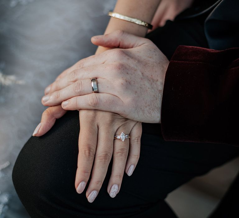 The groom wears a plain silver wedding band with the bride wearing rose gold engagement ring and silver wedding band 