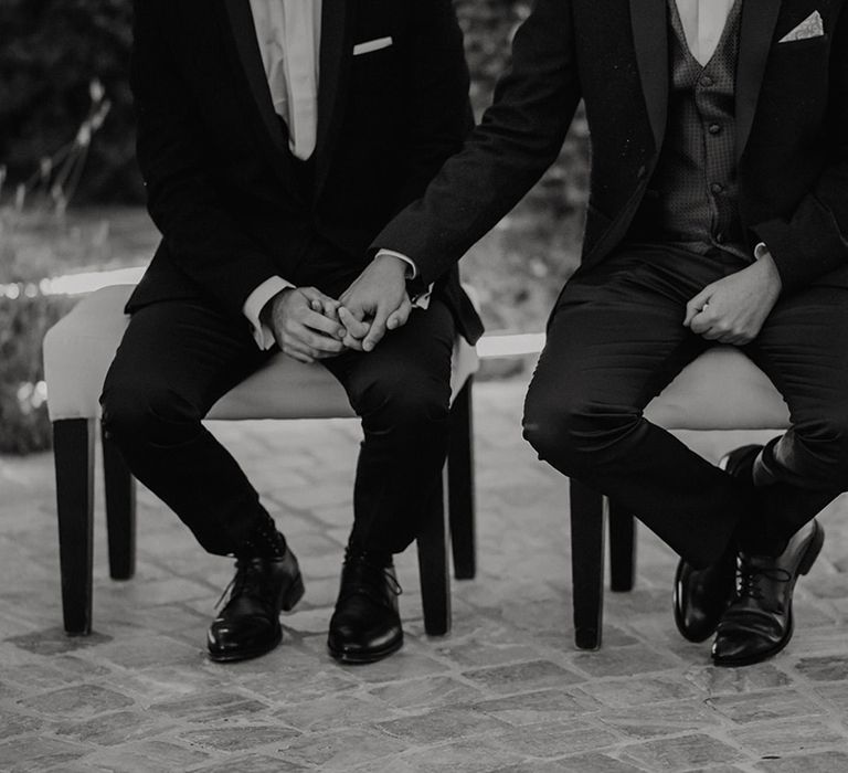 Grooms holding hands during their wedding ceremony 