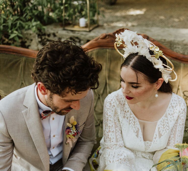 Bride in white floral bridal crown and red lip bridal makeup with groom in greige suit at outdoor wedding in Italy