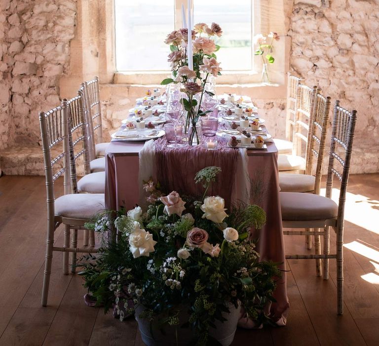 Modern wedding tablescape with lavender tablecloth, lilac tulle table runner, blush garden rose centrepieces, tea light candles and a trio of mini desserts at Pentney Abbey wedding venue 