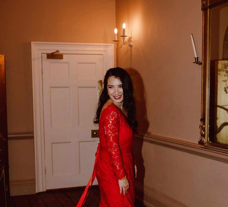 Bride at The Orangery Maidstone spinning around wearing red lace wedding dress with long sleeves, red and gold hair accessories and golden closed toe wedding heels