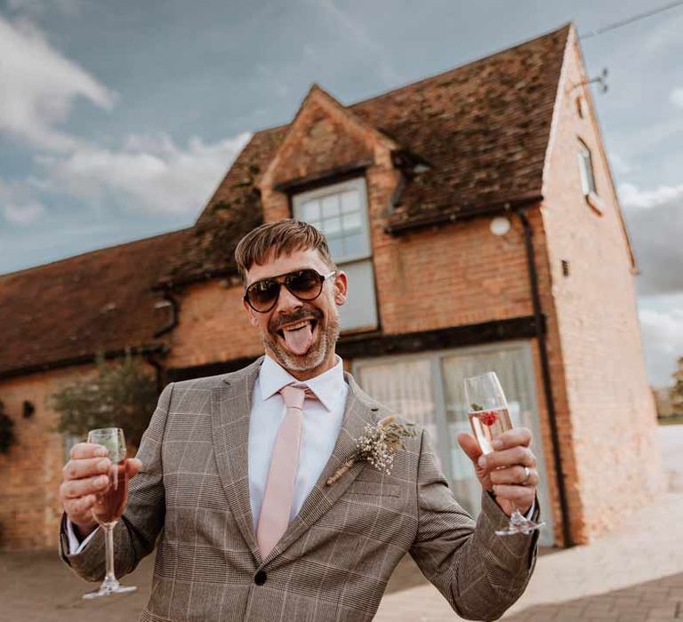 Wedding guest in light grey checkered suit, pink tie and dried flower autumnal boutonniere 