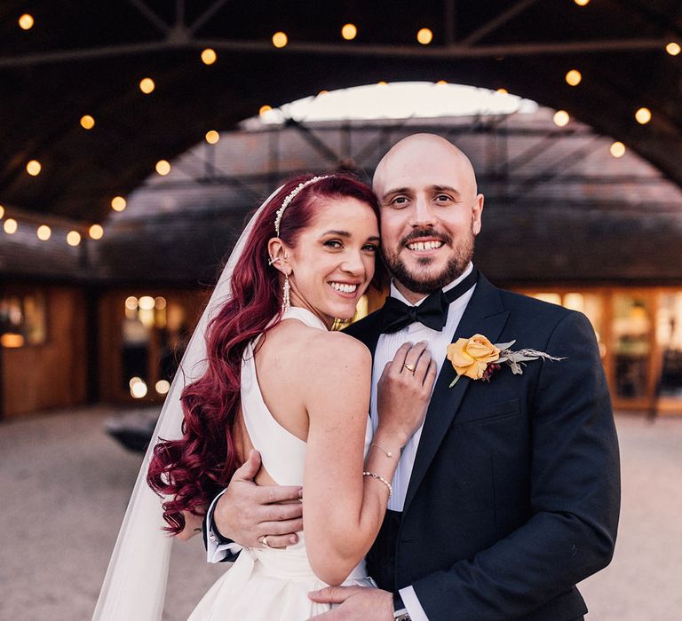 The bride and groom pose together at the modern and industrial Old Gore Barn wedding venue in the Cotswolds