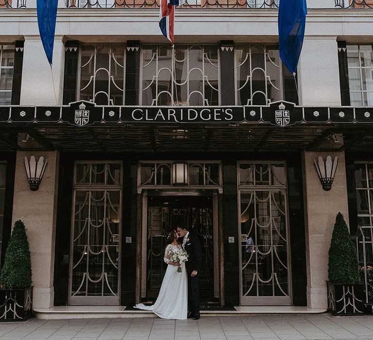 Claridge's wedding in London hotel wedding venue with the bride and groom posing together at the entrance 