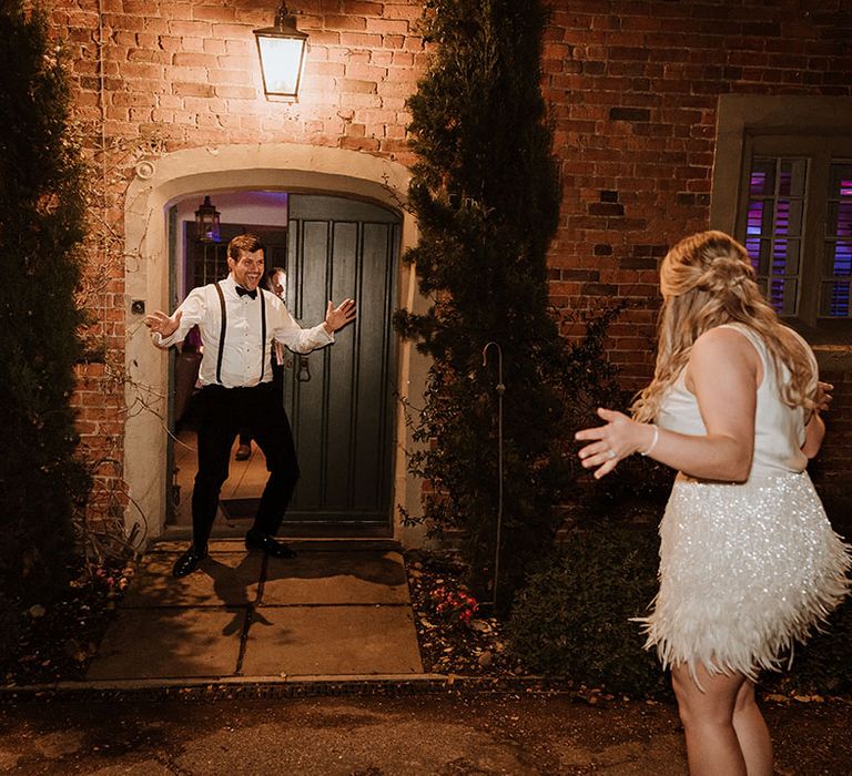 Bride in sleeveless white top with sparkling white tassel short skirt for the wedding reception with the groom in white shirt and black trousers