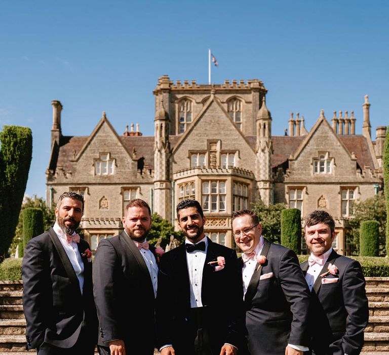 Groom and groomsmen in black tie pose together at the De Vere Tortworth Court wedding 