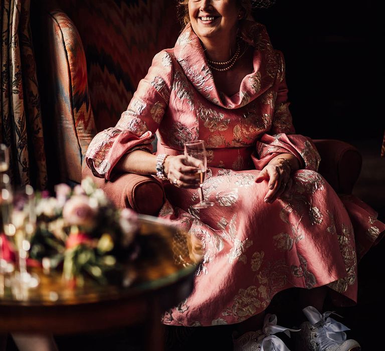 Mother of the bride wearing a pink dress with gold embroidery with vintage style blue wedding shoes 