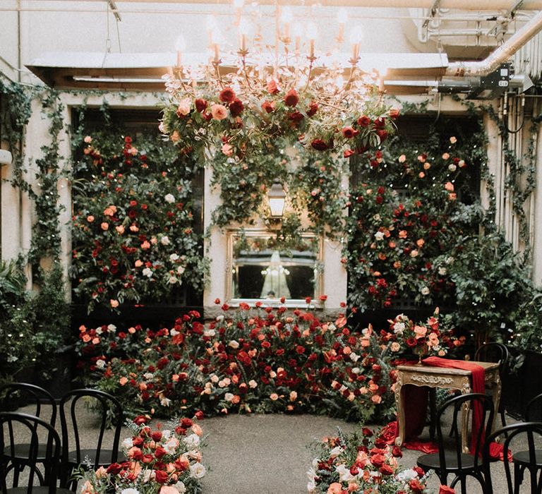 Red, orange, and white wedding flowers decorating the aisle and the altar with roses and poppies 