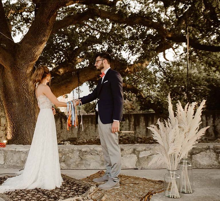 outdoor wedding ceremony for greece destination wedding with handfasting ritual pampas grass and wool rug decor