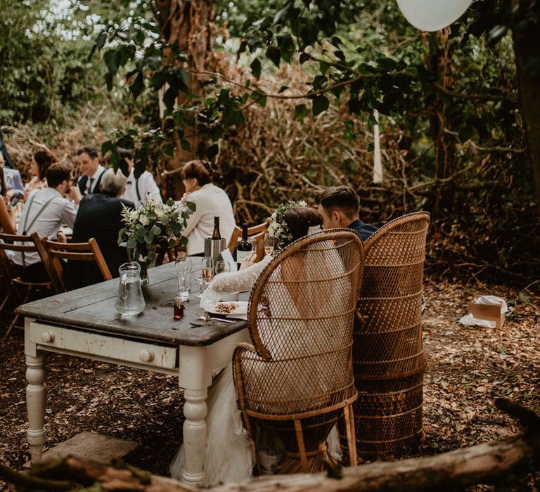 Bride and groom sit separately from their wedding guests at a sweetheart table 