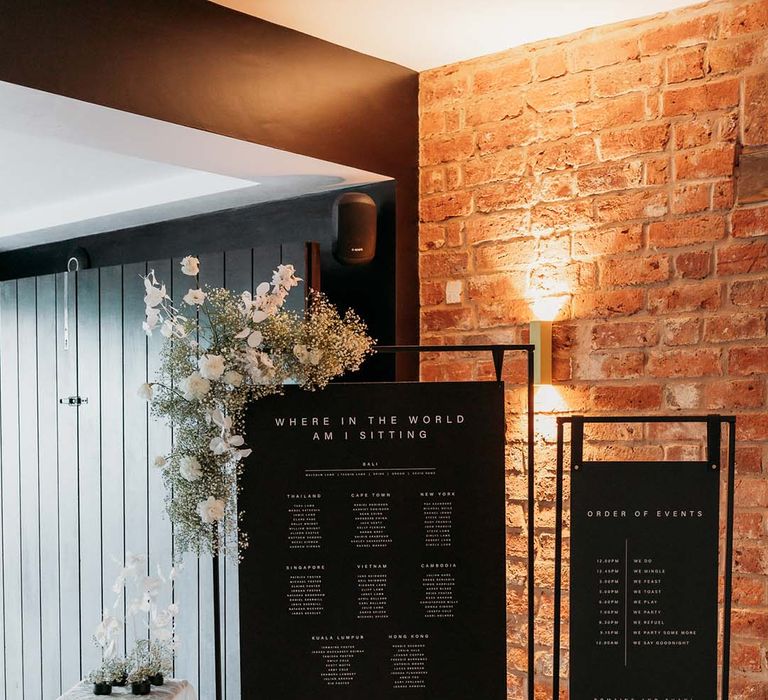 Black contemporary seating chart with white flower decor on metal frames