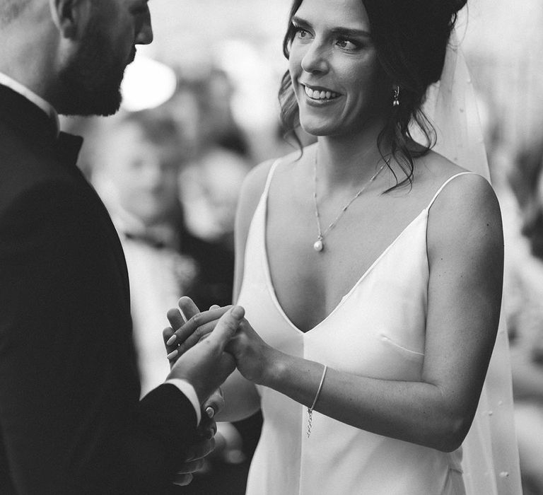 Bride holds hands with the groom at their outdoor wedding ceremony 