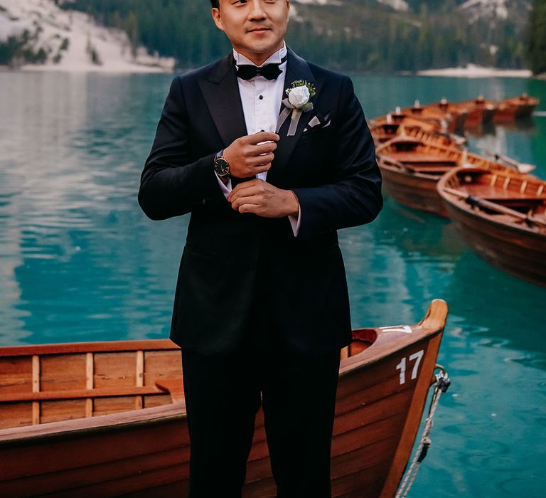 Groom in black tuxedo with white rose buttonhole at destination wedding 