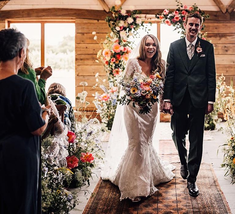 Botanical aisle and altar decorations for The Cherry Barn with the bride and groom walking back down the aisle as a married couple 