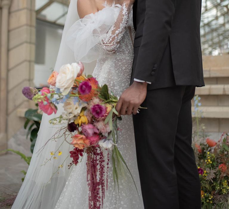 Bride in long sleeve lace wedding dress with the groom wearing a black tuxedo 