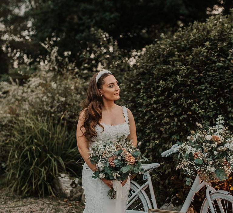 Bride in custom wedding dress with white headband and neutral wedding bouquet 