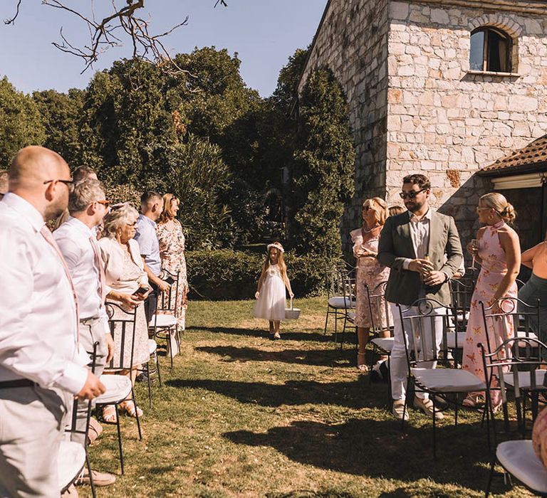 Flower girl starts the walk down the aisle at outdoor Croatian wedding ceremony 