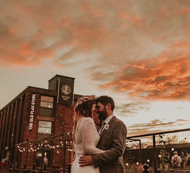 Golden hour couple portrait with the bride and groom embracing as the sun sets 