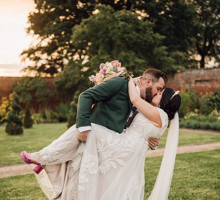 Epic dip kiss wedding photo with bride wearing pink metallic shoes with princess wedding dress 