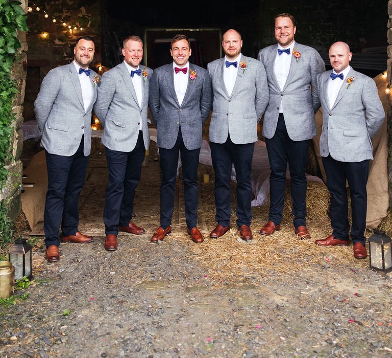 Groomsmen wearing light grey wedding suit jackets with groom in dark grey wedding suit 