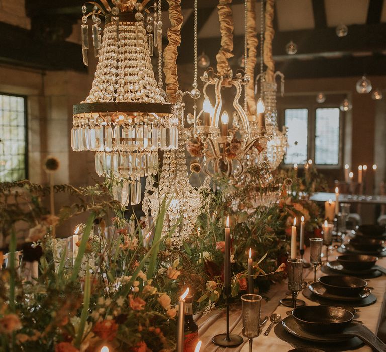 Intimate wedding reception with chandelier lighting, candles and flower centrepiece decor 