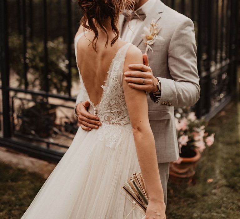 Bride in backless Watters wedding dress with Groom in garden