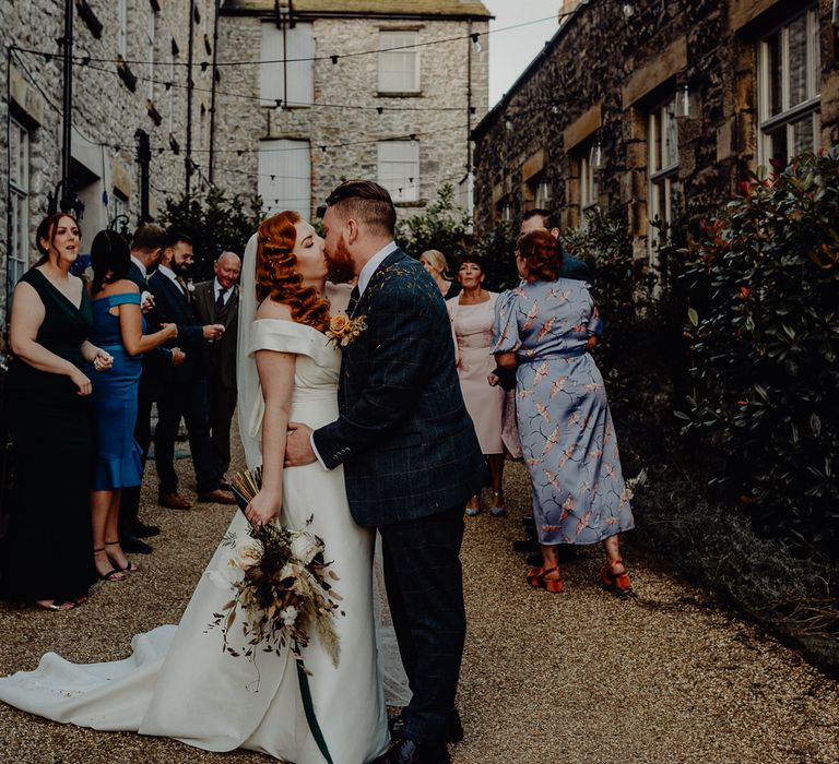 Bride with vintage wedding hair kissing her groom at the end of the confetti exit 