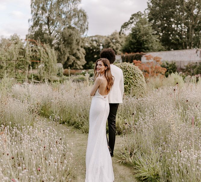 Bride with long brown hair and red lipstick walking through the gardens at Middleton Lodge 