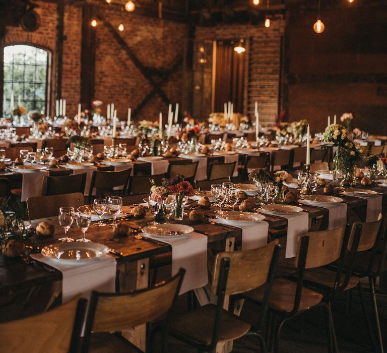 Rustic wedding reception at Les Bonnes Joies with festoon and fairy lights, banquet tables and flower stems in bottles