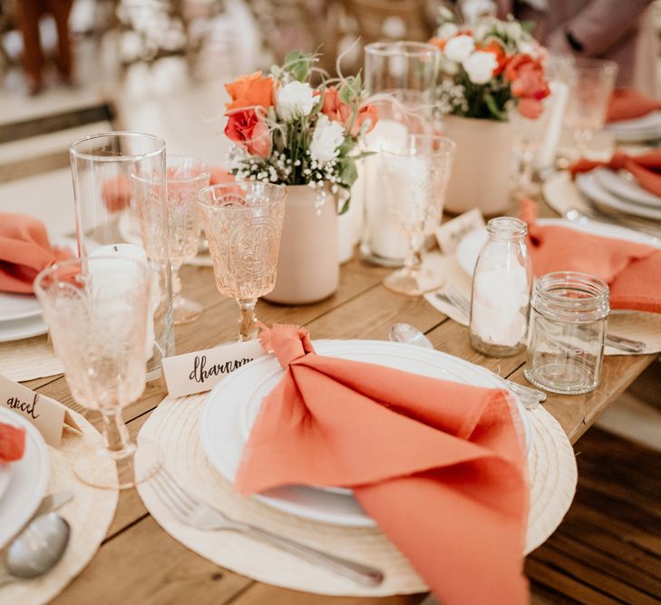 Peach, coral and beige wedding table decor with wicker placemats, colourful napkins and glassware