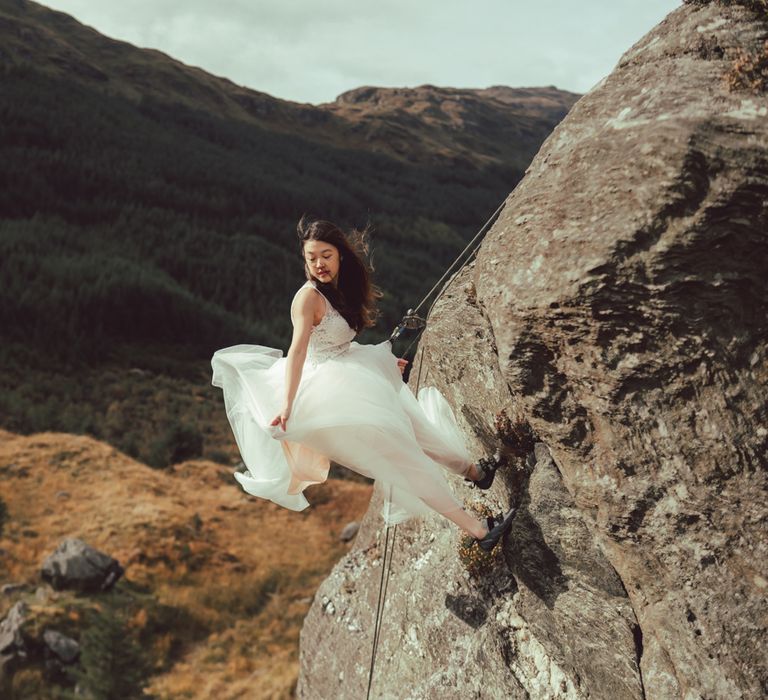 Dark haired girl during rock climbing engagement session 