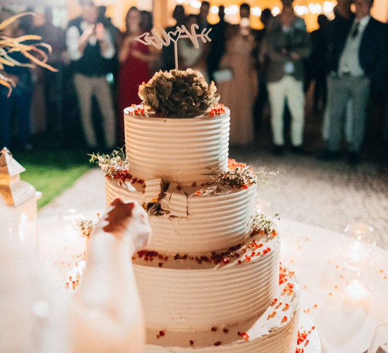 Cutting into their huge white iced four tier wedding cake