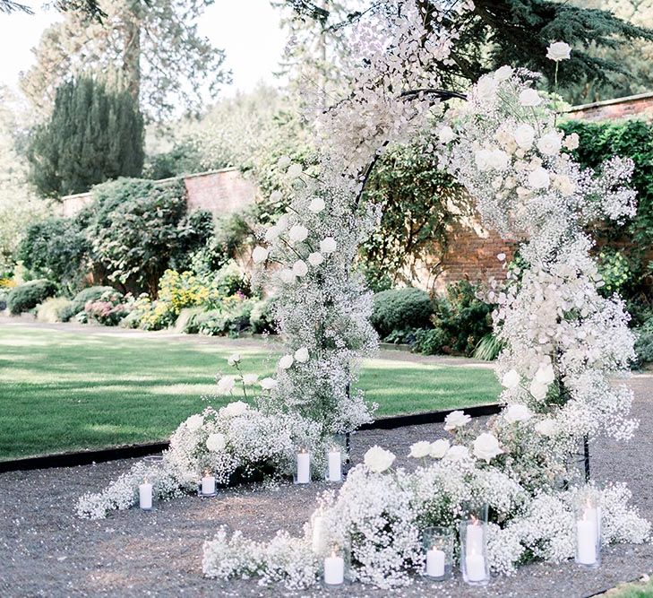 White gypsophila and rose floral arch with pillar candles 