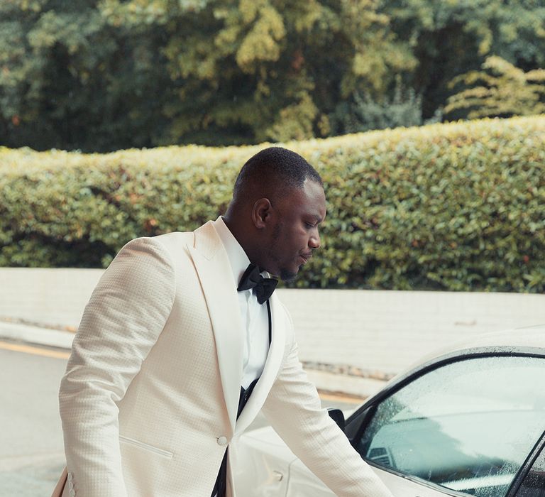 Groom reaches for door handle of car on his wedding day