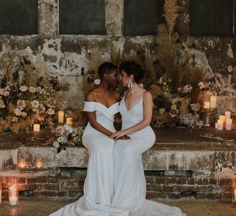 Two brides sitting at The Asylum altar in Made With Love Bridal gowns 