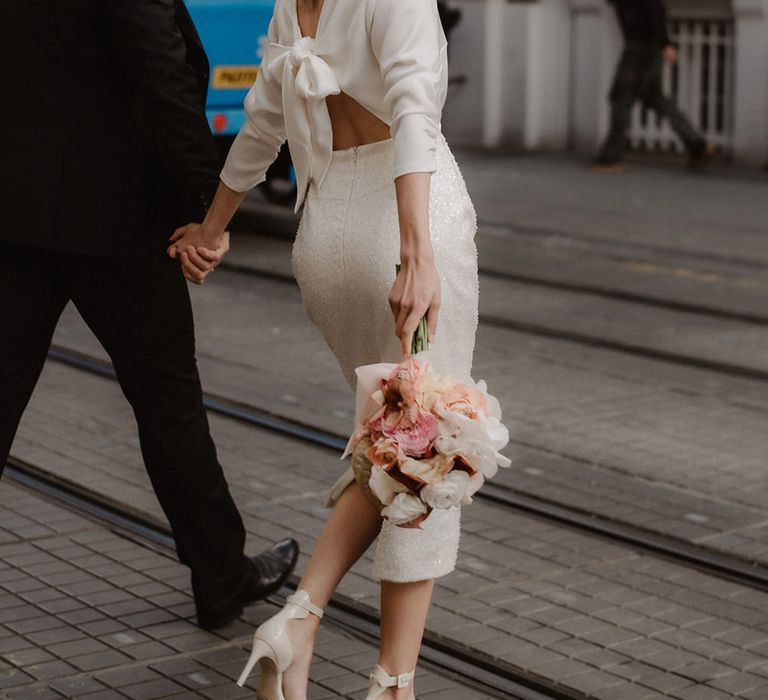 Stylish city wedding with bride in a midi dress with back bow detail wearing a blush wedding veil 