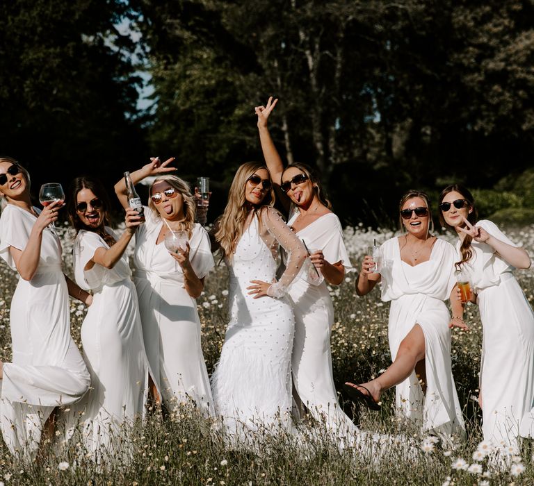 Bride stands with bridesmaids outdoors as they celebrate