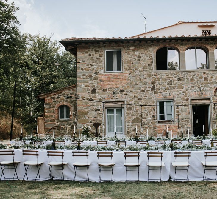 Outdoor wedding reception in Tuscany with white linen and candles and a foliage table runner 